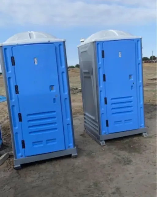 Blue construction porta potties on a dirt jobsite