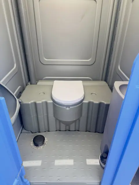 Inside a standard porta potty with seat and vent