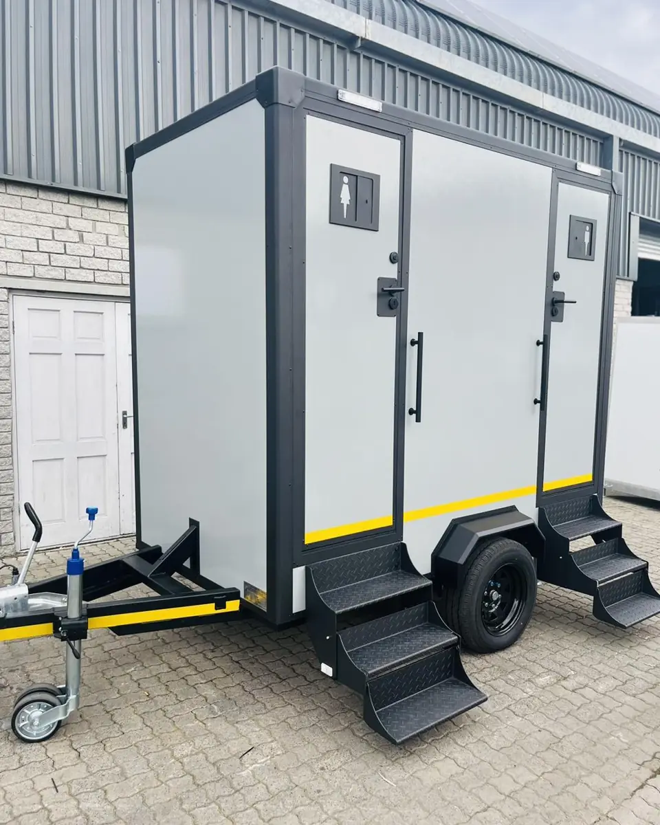 White two-stall restroom trailer with steps and handrails